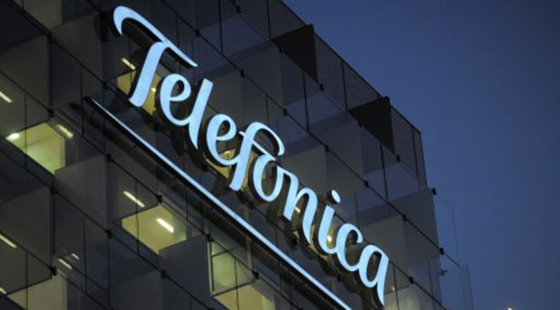 The logo of Telefonica SA hangs illuminated outside the company's headquarters in Madrid, Spain, on Tuesday, Nov. 29, 2011. Telefonica SA, Spain's dominant telecommunications company, aims to complete a review of its online assets such as social networking site Tuenti and the Jajah Web-phone unit early next year. Photographer: Denis Doyle/Bloomberg