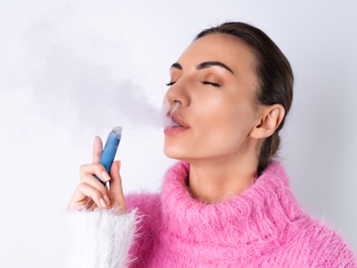mujer joven usa vaper desechable