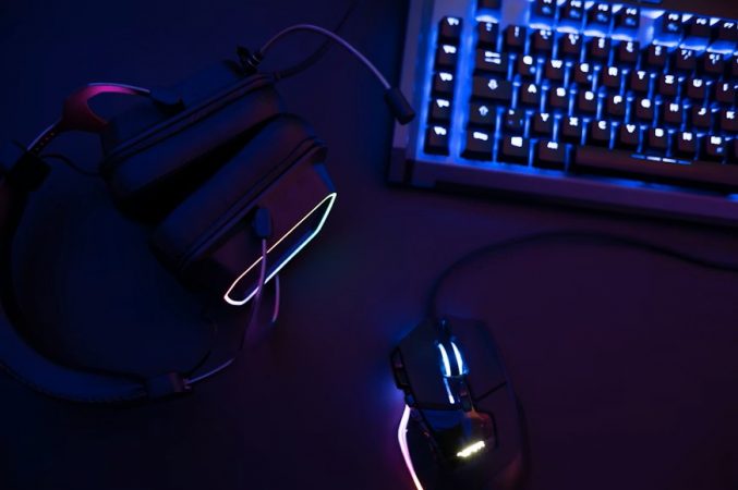 Auriculares, ratón y teclado con retroiluminación LED en una mesa oscura